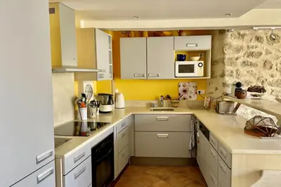 a kitchen with yellow walls and white cabinets at Village house Stella in Saint-Cannat