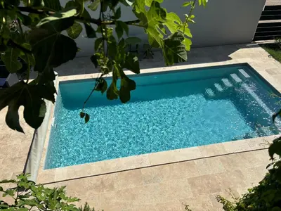a swimming pool with blue water in a yard at La Cassiopée in Caromb