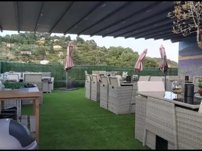 a patio with chairs and tables on a green lawn at Luberon family in Apt