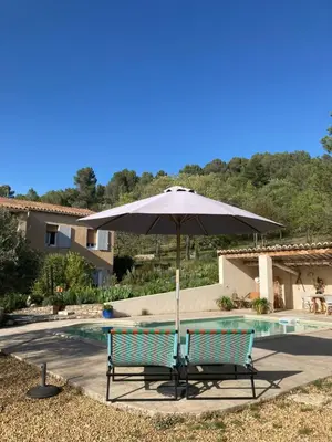an umbrella sitting next to a swimming pool at Les Lavandes in Saignon