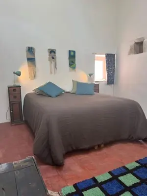 a bedroom with a large bed with blue pillows at Luberon en Provence - La maison de Michèle au cœur de Goult in Goult
