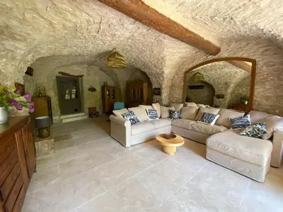a living room with white couches and a stone wall at Luberon en Provence - La maison de Michèle au cœur de Goult in Goult