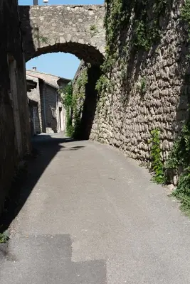 an alley with an archway in a stone wall at Gite au nid d'Ange in Lincel