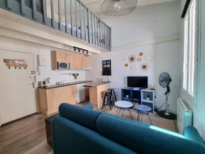 a living room with a blue couch and a kitchen at Joli studio en plein centre historique in Aix-en-Provence