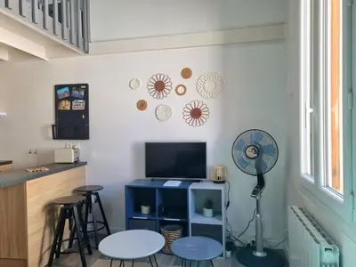 a living room with a tv and stools and a fan at Joli studio en plein centre historique in Aix-en-Provence