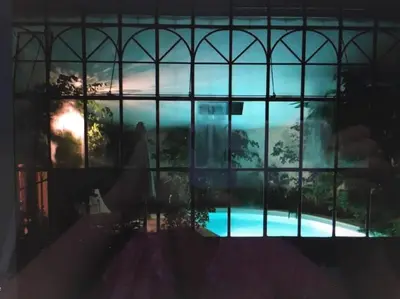 a view of a swimming pool through a window at Ecolodge Au fil de l'eau, avec piscine intérieure et parc arboré in Lagnes