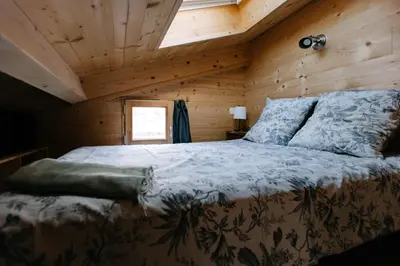 a bedroom with a bed in a wooden cabin at Charming Tiny House in LʼIsle-sur-la-Sorgue
