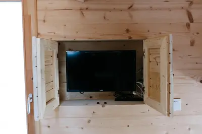 a tv in a wooden room with a wall at Charming Tiny House in LʼIsle-sur-la-Sorgue
