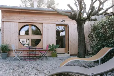 a tiny house with a round window and a table and chairs at Charming Tiny House in LʼIsle-sur-la-Sorgue