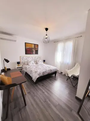 a white bedroom with a bed and a table at La Villa aux Cyprès bleu in Le Thor