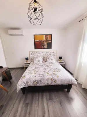 a bedroom with a bed and a chandelier at La Villa aux Cyprès bleu in Le Thor