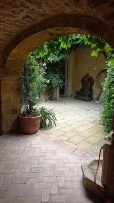 an archway with plants and a fountain in a courtyard at Clos des Jasmins avec sa jolie cour intérieure in Lourmarin