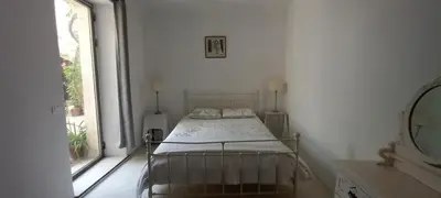 a bed in a white room with a window at Clos des Jasmins avec sa jolie cour intérieure in Lourmarin
