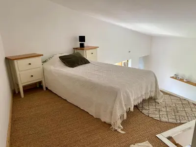 a white bedroom with a bed and a night stand at A 20 minutes de Aix en Provence in Pertuis