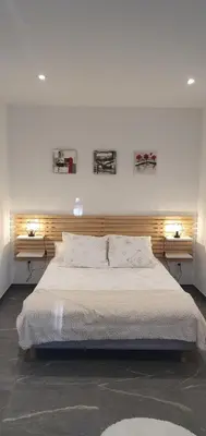 a bedroom with a large bed with two lights on the wall at CHRIS LE VERGER in Saignon