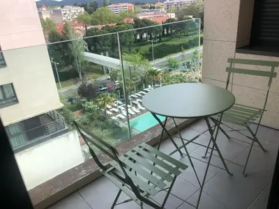 a table and chairs on a balcony with a view of a pool at ITER House \uc774\ud130 \ud558\uc6b0\uc2a4 in Aix-en-Provence