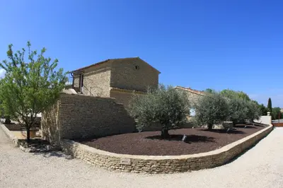a stone retaining wall with trees in front of a building at Les Pres de Gordes in Gordes