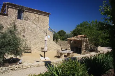 a stone building with a table and a bench in a courtyard at Les Pres de Gordes in Gordes