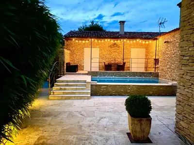 a house with a swimming pool with lights on it at Les Pres de Gordes in Gordes