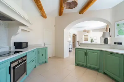 a kitchen with green cabinets and an archway at La Bastide Des As in Gordes