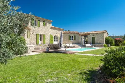 a stone house with a pool and a yard at La Bastide Des As in Gordes