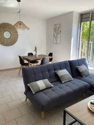 a blue couch in a living room with a table at Spacieux 2 chambres, CLIM, parking prive ferme, LOCAL VELOS in Entraigues-sur-la-Sorgue