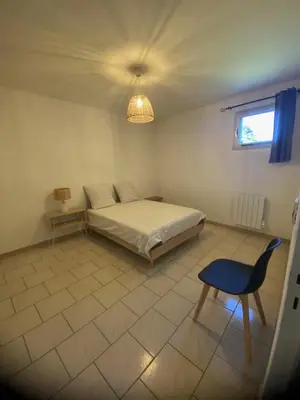 a bedroom with a bed and a chair and a chandelier at Spacieux 2 chambres, CLIM, parking prive ferme, LOCAL VELOS in Entraigues-sur-la-Sorgue