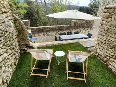 a patio with two chairs and a table and an umbrella at Villa luxueuse à Ménerbes + piscine in Ménerbes