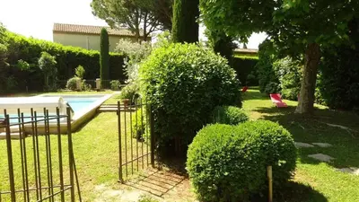a garden with a pool and some bushes and a fence at Villa élégante à Cavaillon avec piscine in Cavaillon