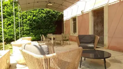 a patio with wicker furniture and a table and chairs at Villa élégante à Cavaillon avec piscine in Cavaillon