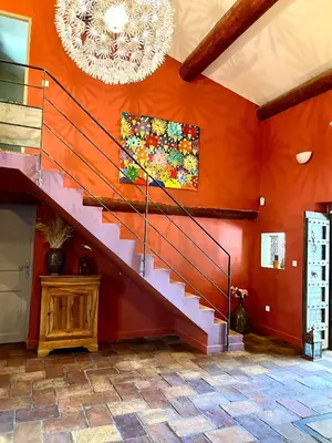 a staircase in a room with orange walls and a chandelier at Villa Mireyos in Rognes
