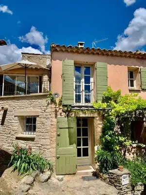 an old stone house with green doors and windows at Maison Joucas in Joucas