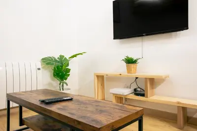 a living room with a wooden table and a tv on the wall at Studio Aixois Mezzanine in Aix-en-Provence