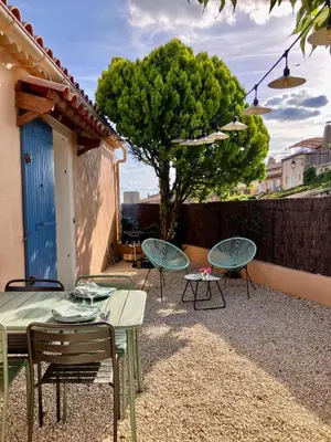 a patio with tables and chairs and a tree at La maison des cerisiers in Bédoin