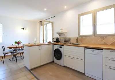 a kitchen with a sink and a washing machine at La maison des cerisiers in Bédoin