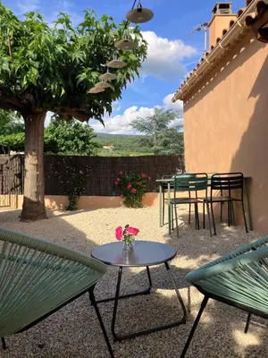 a patio with green chairs and tables and a tree at La maison des cerisiers in Bédoin