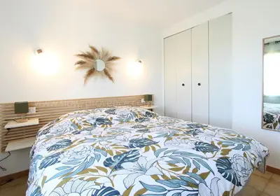 a bedroom with a bed with a blue and white bedspread at La maison des cerisiers in Bédoin