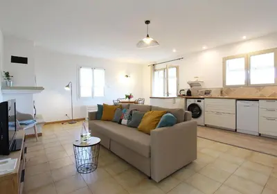 a living room with a couch and a kitchen at La maison des cerisiers in Bédoin