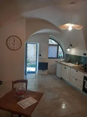 a kitchen with a table and a clock on the wall at Petit bonheur in Lauris