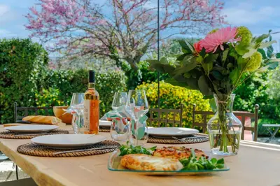 a table with plates of food and a vase of flowers at Lou Karo - Piscine partagée - Parking privé in Gordes
