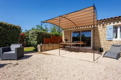 a pavilion with chairs and a table in a yard at Lou Karo - Piscine partagée - Parking privé in Gordes