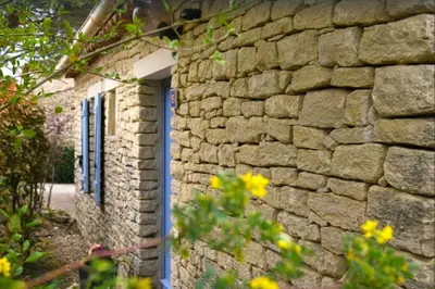 a stone building with a blue door and windows at Lou Karo - Piscine partagée - Parking privé in Gordes