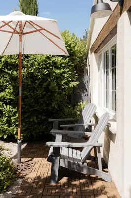 two white chairs and an umbrella on a patio at LE MAS DE LA TERRE - Chambres d'hôtes in LʼIsle-sur-la-Sorgue