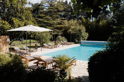 a pool with chairs and a table and an umbrella at LE MAS DE LA TERRE - Chambres d'hôtes in LʼIsle-sur-la-Sorgue