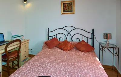 a bedroom with a bed with red pillows and a desk at Beautiful Home In La Bastide-Des-Jourdan in La Bastide-des-Jourdans