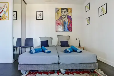 two beds in a room with blue pillows at Sérénité au fil de l'eau Appartement de standing in LʼIsle-sur-la-Sorgue