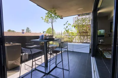 a room with a balcony with a table and chairs at Sérénité au fil de l'eau Appartement de standing in LʼIsle-sur-la-Sorgue