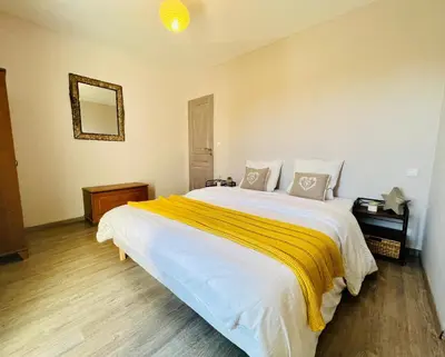 a bedroom with a large white bed with a yellow blanket at La villa Louca in Saint-Saturnin-les-Apt
