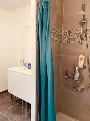 a bathroom with a blue shower curtain next to a sink at Charmante maison de vacances en Luberon in Beaumettes