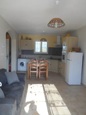 a kitchen with a couch and a table and a refrigerator at Le Cabanon d'Amandine et Gabriel in Blauvac
